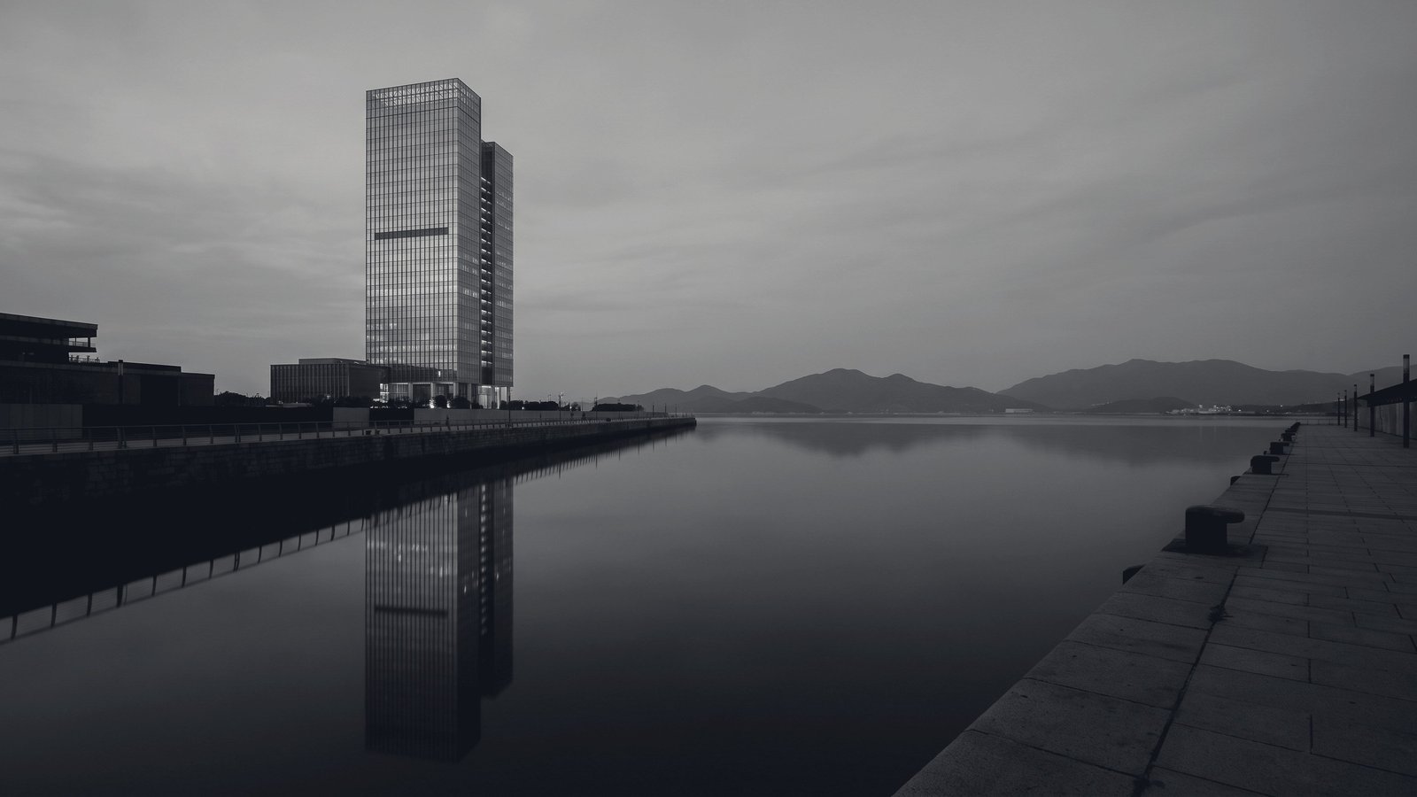 A single tower on a harbour front under flat grey light.